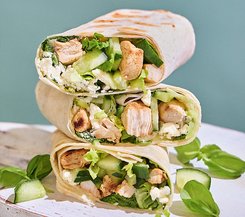 Gesunde Wraps mit gegrilltem Hähnchen und Feta Drei gesunde Wraps gefüllt mit gegrilltem Hähnchen, frischen Gurken, Salat und Feta-Käse, auf einem weißen Untergrund präsentiert.